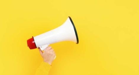A person holding a white megaphone on a yellow background