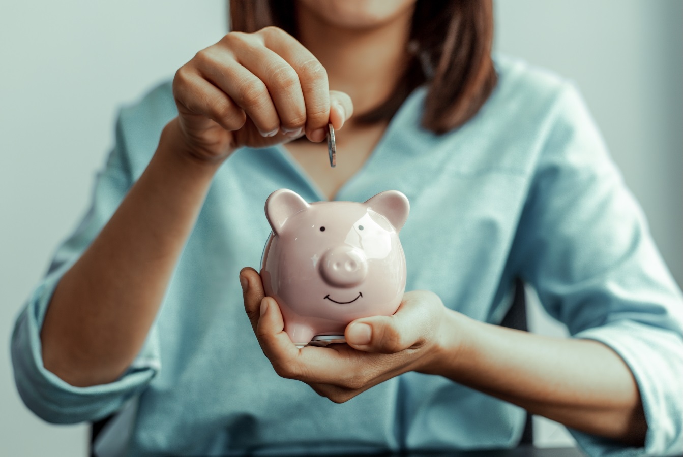 Woman placing coin in piggy bank