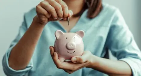 Woman placing coin in piggy bank