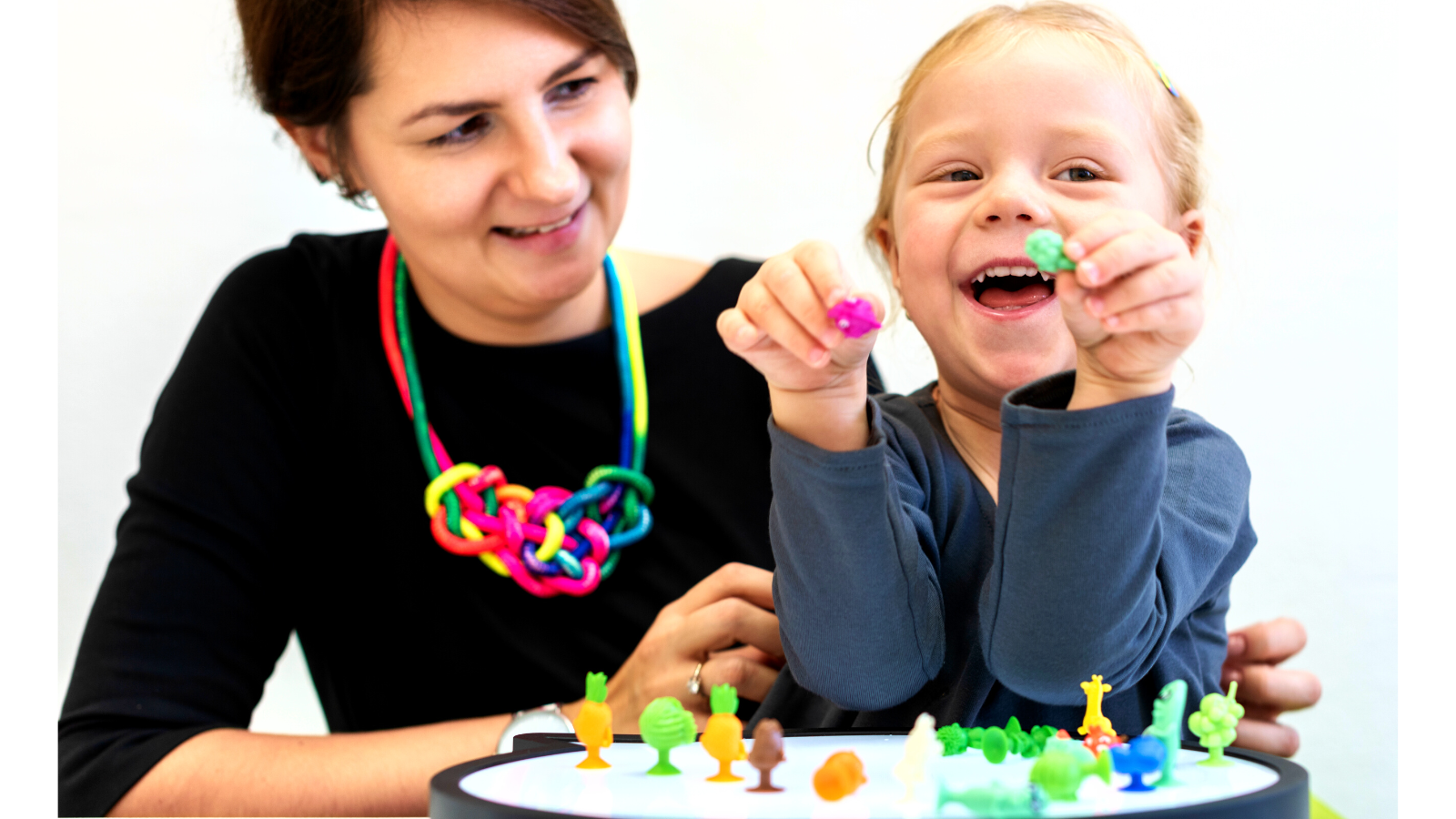 Child playing with toys on a peg board with a woman helping her