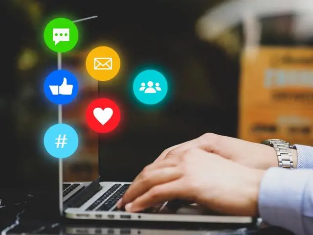 Someone using a laptop, with social media icons in background