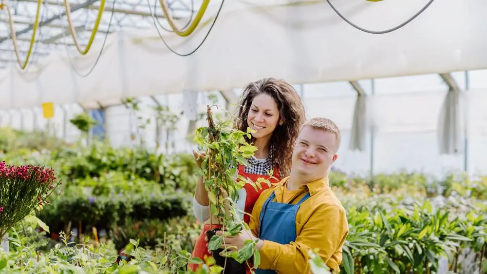 A young man with additional needs working in a garden centre