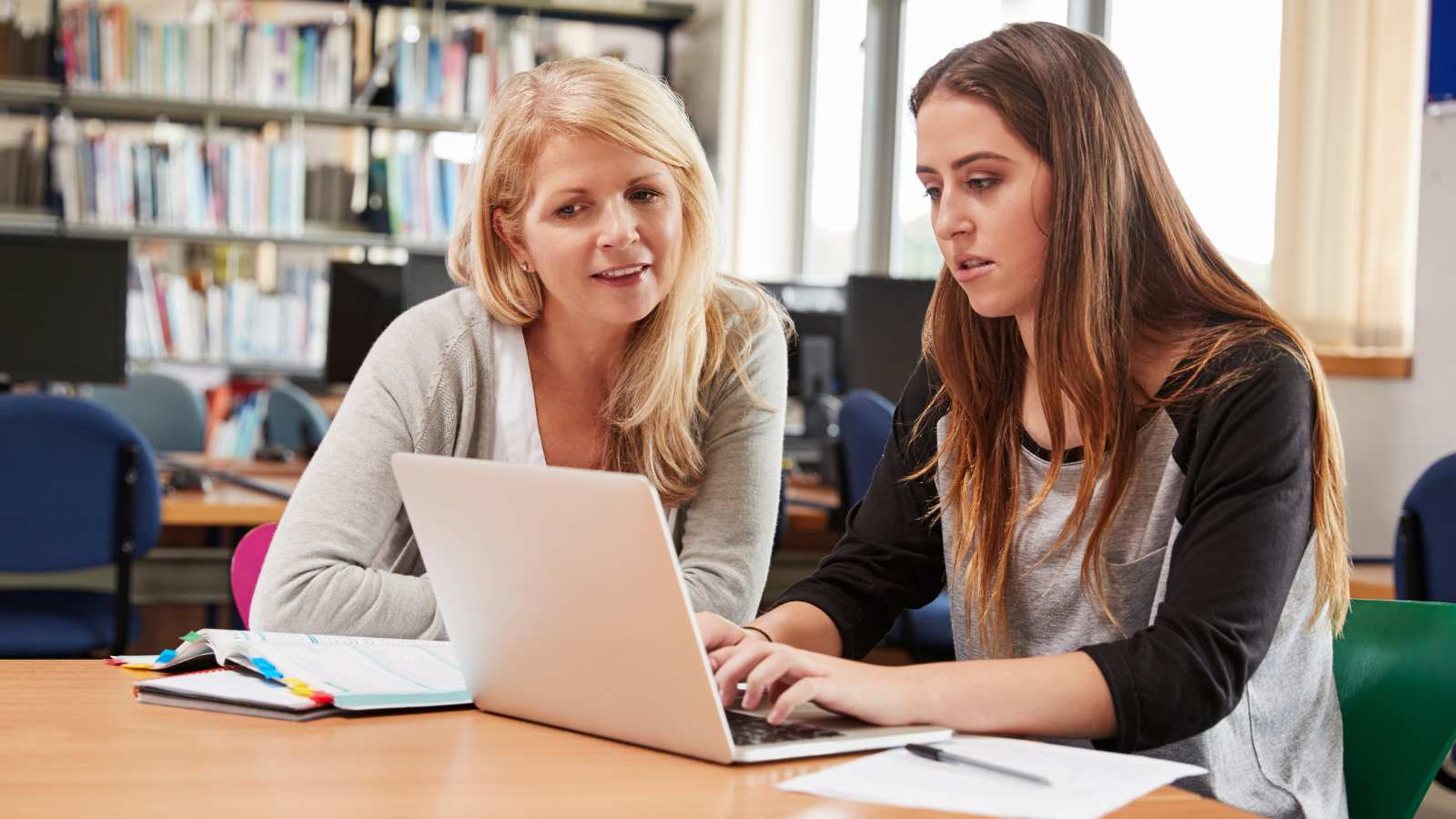 Tutor with teenage girl looking at laptop