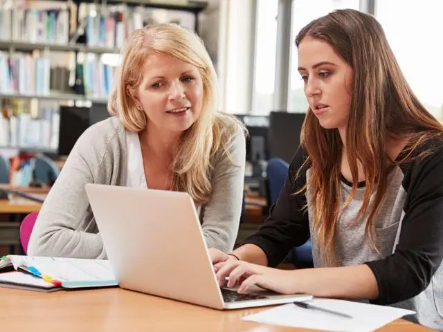 Tutor with teenage girl looking at laptop