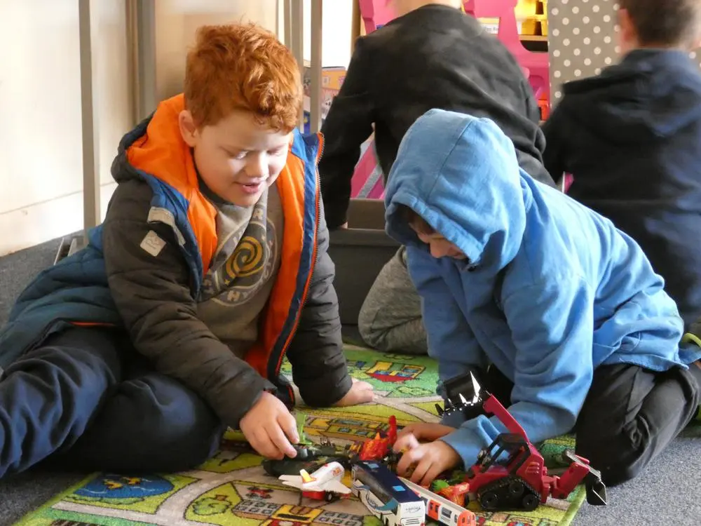 two children playing with toy vehicles
