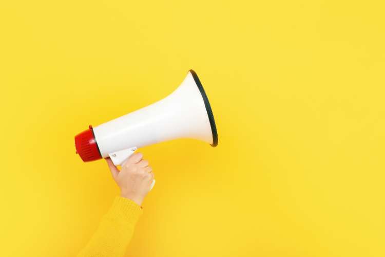 A person holding a white megaphone on a yellow background